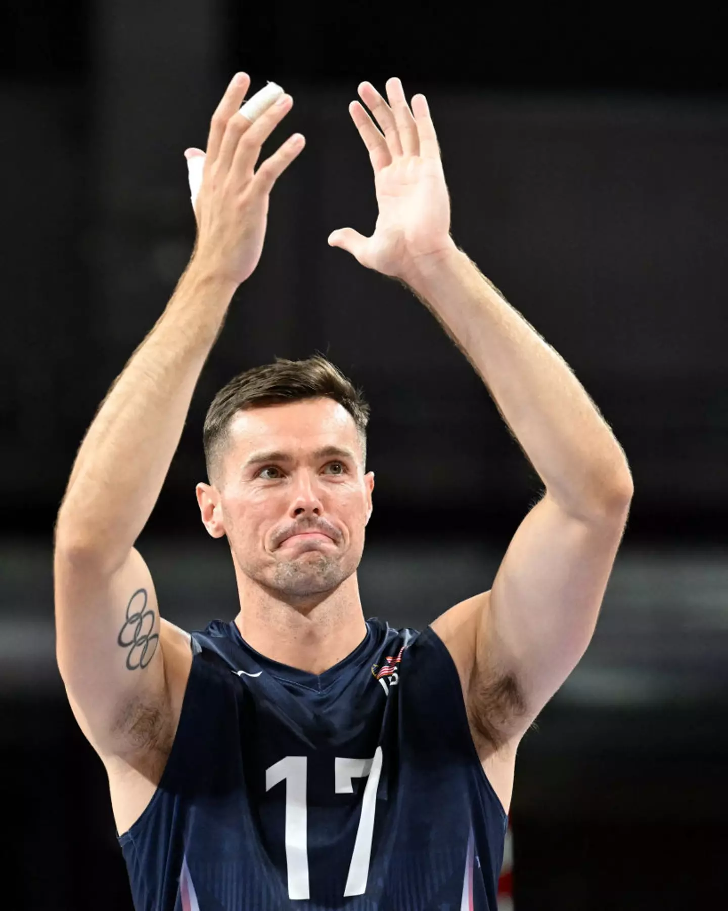 O jogador de vôlei da seleção dos EUA, Thomas Jaeschke, comemora após derrotar a Alemanha nas Olimpíadas de Paris 2024 com sua tatuagem em plena exibição.