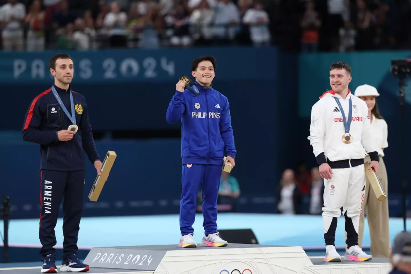 O medalhista de ouro Carlos Yulo sobe ao pódio no evento de salto masculino.