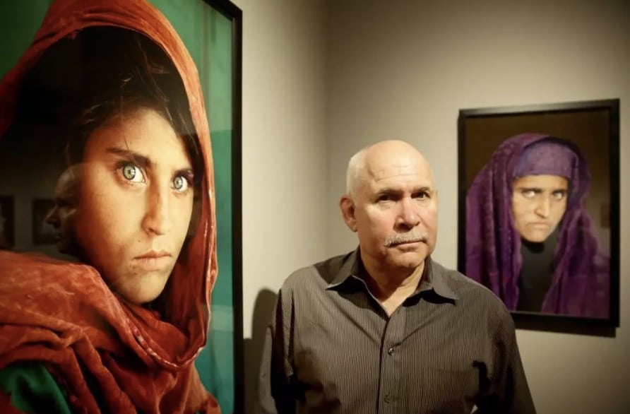 Pessoas estão apenas descobrindo a verdade comovente por trás da famosa foto da "menina afegã" — e isso vai mudar a maneira como você a vê para sempre. Steve McCurry posed next to the photo at the Overwhelmed by Life exhibition in Germany